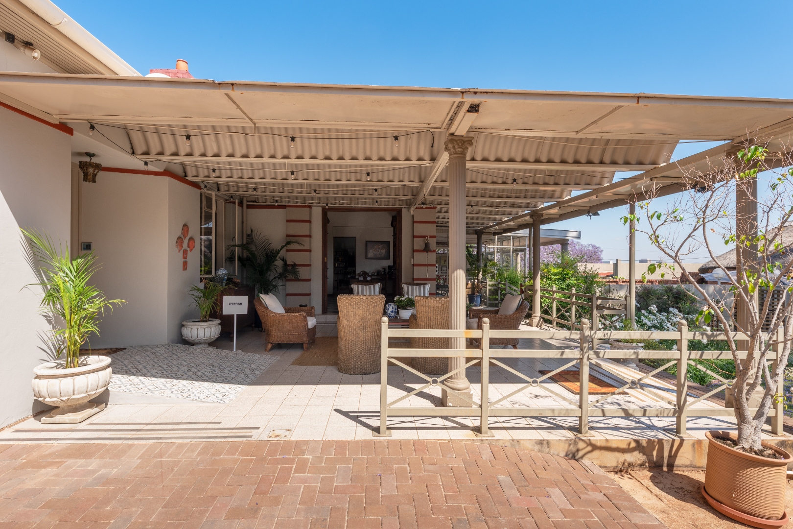 Covered veranda with wicker armchairs and jacaranda-lined view