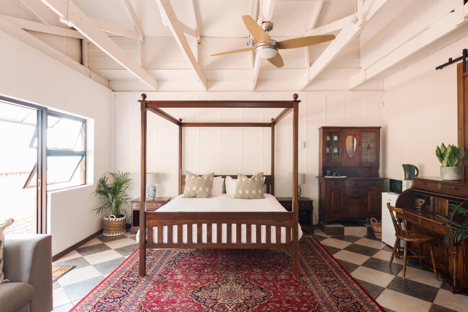 Deluxe King Room with four-poster bed and checkerboard floor at House Falcon Guest House